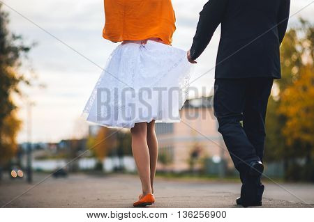 Bride and groom holding handsGroom holds the bride for a dress. Back view. Concept of a hanging wedding in the fall.