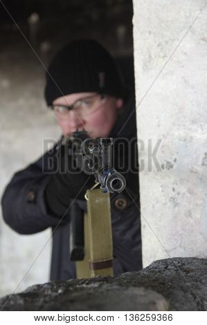 machine gunner in black uniforms and protective glasses aim of the shelter