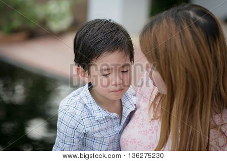 Asian mother embracing and consoling her son