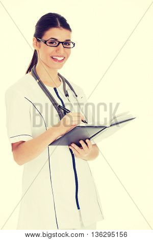 Young female doctor wirting in a book.