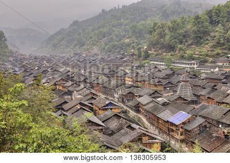 Zhaoxing Dong Village Guizhou Province China - April 7 2010: Tile roofs of wooden houses in the mountain village of Dong ethnic minority misty morning spring.
