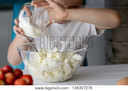Child Adding Sugar To Cottage Cheese In A Bowl.