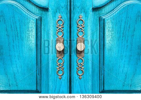 Stylish brass door handles on a hardwood cabinet or closet with ornate escutcheons and raised panels on the doors in a close up frontal view conceptual of furnishing and interior decor