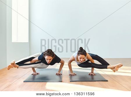 Two Young Women Doing Yoga Asana Eight-angle Pose