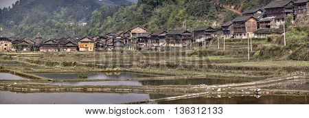 Zhaoxing Dong Village Guizhou Province China - April 8 2010: Panoramic view of village ethnic minorities in southwestern China wooden huts on background of mountains near rice fields spring.