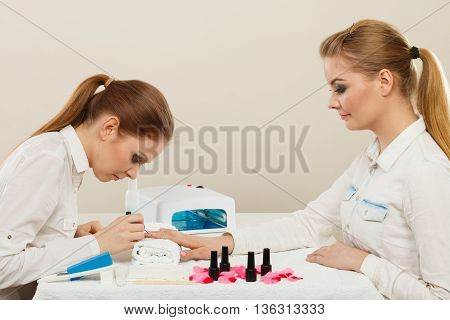 Relaxing time and wellness day concept. Blonde elegant woman visiting professional manicurist salon. Beautician makes perfect nails to client.