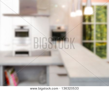 Modern kitchen furnishing with desk oven window and lights blurred.