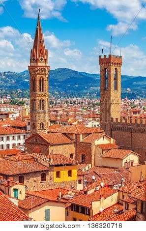 Tower of palazzo vecchio in florence top view to tile roofs old town blue mountains landscape on background italy