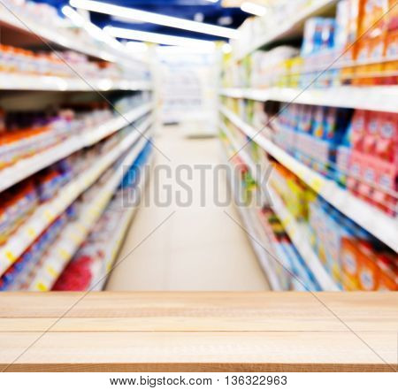 Wooden board empty table in front of blurred background. Perspective light wood table over blur of baby foods jars in store. Mock up for display or montage your product.