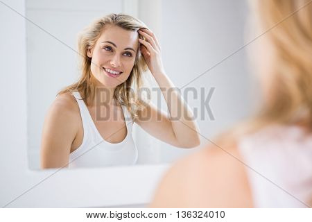 Young woman checking her hair in bathroom mirror at home