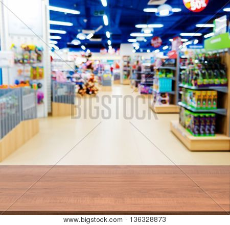 Wooden board empty table in front of blurred background. Perspective dark wood table over blur in kids toy store. Mock up for display or montage your product.