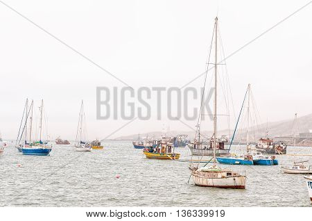 LUDERITZ NAMIBIA - JUNE 14 2011: Sail yachts and fishing boats in misty conditions at the harbor in Luderitz in Namibia