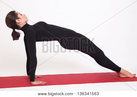 Beautiful athletic girl in black suit doing yoga. Purvottanasana asana plank pose. Isolated on white background.