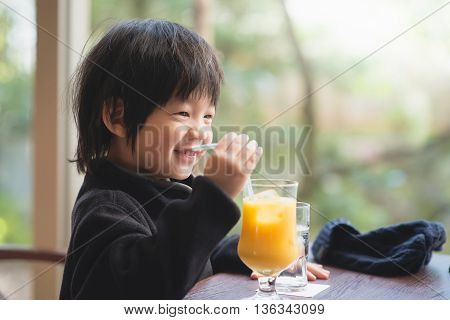 Cute asian child drinking fresh orange juice
