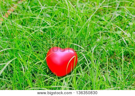 red heart shape on grass abstract background metaphor to lonely love or neglect the act of being uncased for. for Valentine's day season concept.