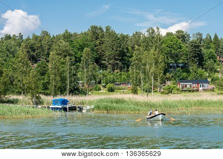VIKBOLANDET, SWEDEN - JUNE 25, 2016:  People relax in a rowboat during midsummer at Vikbolandet. Midsummer is one of the major holidays in Sweden.