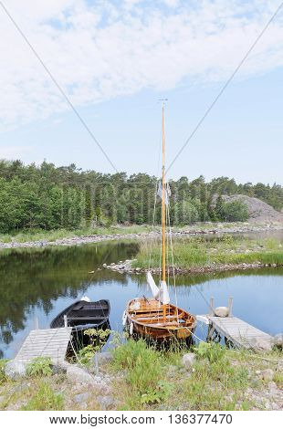 Rural wooden rowboat and sailboat at small bridges in the bay. No people