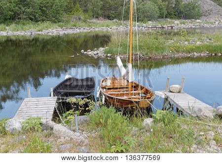 Rural wooden rowboat and sailboat at small bridges in the bay. No people