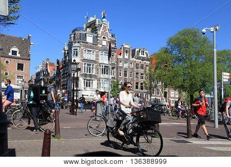 AMSTERDAM, NETHERLANDS - MAY 8, 2016: Local people on bicycle in historical center in Amsterdam, the Netherlands. Bicycles outnumber people in Amsterdam: 760000 citizens and nearly a million bikes.