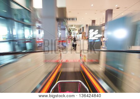 Blur image of people walking down the escalator at airport