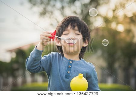 Cute asian child is blowing a soap bubbles