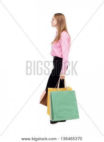 back view of going  woman  with shopping bags . beautiful girl in motion.  backside view of person.  Rear view people collection.  The girl in the pink shirt is bent under the weight of the bags.