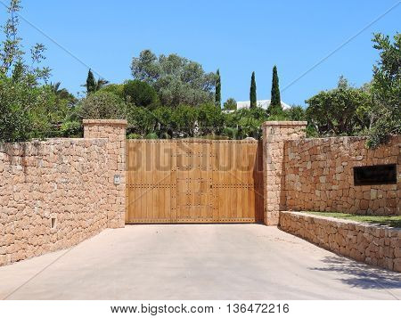 Wooden gate of a mansion with drystone wall and security system.
