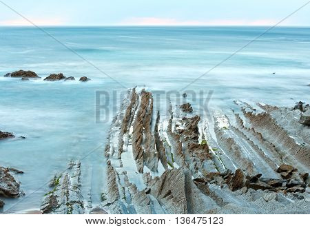 Twilight Ocean Coast With Ribbed Stratiform Rock.