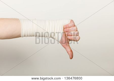 Bad news and information. Medicine aspects. Male hand with bandage showing thumb down sign symbol.