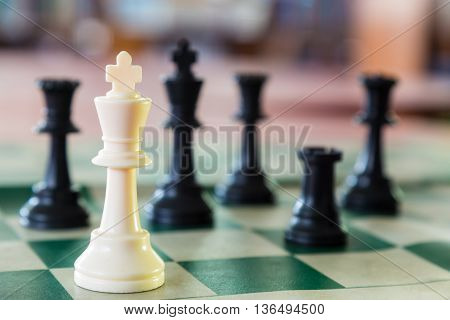 White chess king alone surrounded by the opposite pieces selective focus on white chess king piece