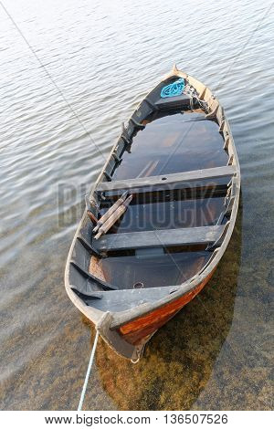 Wooden rowboat in warm evening light partly filled with water to get it waterproof