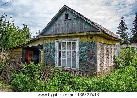 Country-old country house overgrown with grass and tumbled down fence