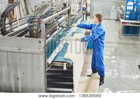 Laundry worker in the process of working on automatic machine for carpet washing in dry cleaning