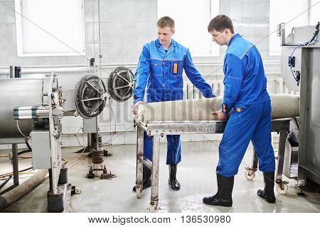 Men workers cleaning get carpet from an automatic washing machine and carry it in the clothes dryer in the Laundry room
