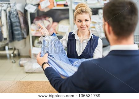 Girl worker Laundry man gives the client clean clothes at the dry cleaners