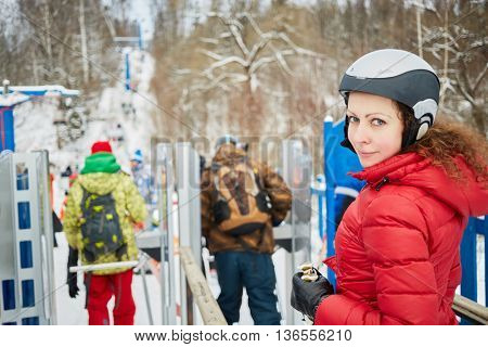 Young woman equipped for skiing near turnstile at ski resort.