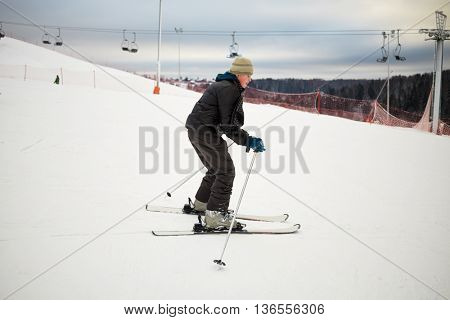 Teenage boy skis on snowy slope at ski resort.