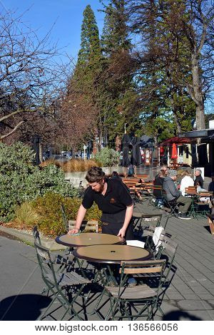 Hanmer Springs New Zealand - June 25 2016: Waiter cleans a table at popular outdoor cafe in the Tourist Town of Hanmer Springs North Canterbury.