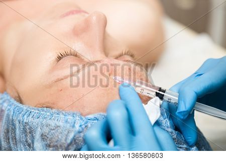 Beautician makes biorevitalization to young woman. The cosmetic procedures for the face. Beauty treatments in the spa salon. Facial Skin Care.