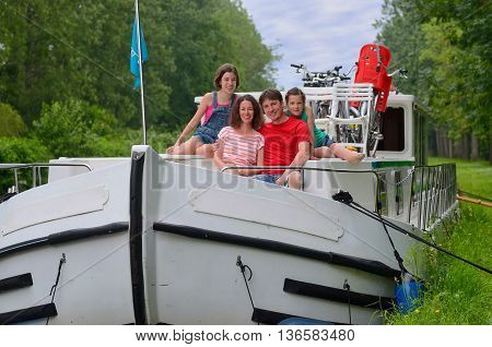 Family vacation, travel on barge boat in canal, happy parents with kids having fun on river cruise in houseboat