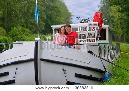 Romantic vacation, travel on barge boat in canal, happy couple having fun on river cruise in houseboat