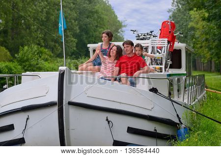 Family vacation, travel on barge boat in canal, happy parents with kids having fun on river cruise in houseboat