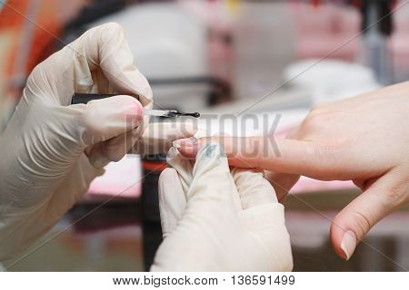 Nails transparent coating is a close-up in a beauty salon. Manicure process.
