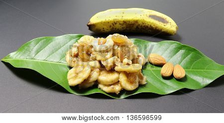 Banana salad or rasayana, a traditional and popular south Indian food, with a topping of raisins and almonds, on a champak leaf.