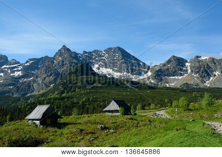 Peaks and two old wooden small huts at trail in Gasienicowa valley in Tatra mountains nearby Zakopane in Poland