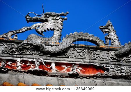 Pengzhou China - October 31 2013: Carved dragon figure sits atop the great hall center roof beam of the Shi Fo Buddhist countryside temple