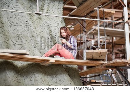 RUSSIA, MOSCOW - MAY 28, 2015: Female sculptor at scuffolding aound clay sculpture to St. Prince Vladimir during manufacture it in the workshop of Salavat Shcherbakov.