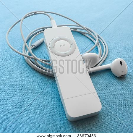 BERRY AUSTRALIA - June 28 2016 : An Apple iPod Shuffle first generation with Apple Earpods attached on a plain blue background.