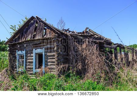 Old wooden abandoned house after the fire overgrown with grass and bushes