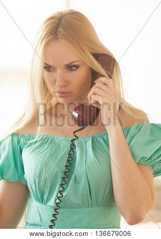 pretty blonde woman in green dress talking on old telephone. Fashion model. Sunny color.